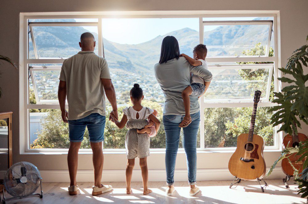 A family gazes out at the mountains through a large window, enjoying the scenic view together